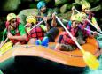 Grupo de pessoas descendo correnteza em um bote inflável usando remos